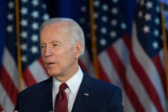 Joe Biden speaking, American flags in the background.