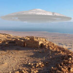 A UFO hovering over a desert landscape with ancient ruins