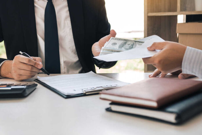 Two individuals engaged in a business transaction involving money and documents