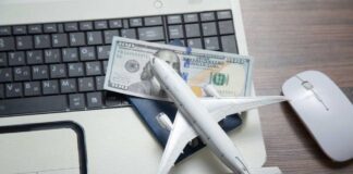 A model airplane on a laptop keyboard with a passport and cash
