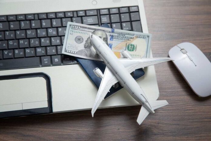 A model airplane on a laptop keyboard with a passport and cash
