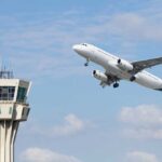 An airplane taking off near an airport control tower