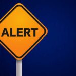 Dire Warning Issued: Americans Trapped! Orange alert sign with the word 'ALERT' displayed prominently