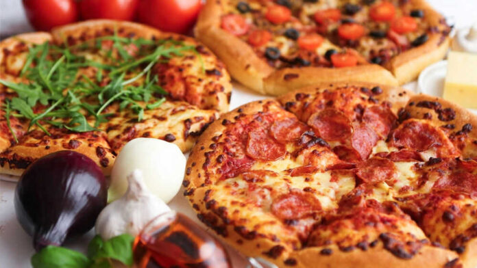 Three pizzas with various toppings and fresh ingredients.