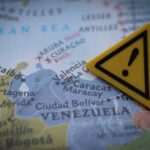 A close-up of a map showing Venezuela with a yellow warning sign