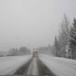 Snow-covered road with a truck driving in a blizzard