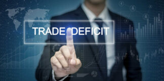 Businessman interacting with a digital display showing 'TRADE DEFICIT'