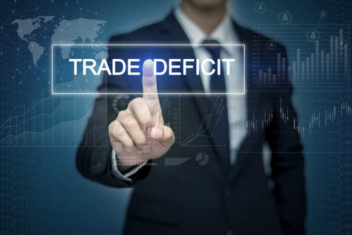 Businessman interacting with a digital display showing 'TRADE DEFICIT'