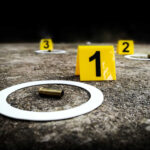 Crime scene with evidence markers and a bullet casing on the ground