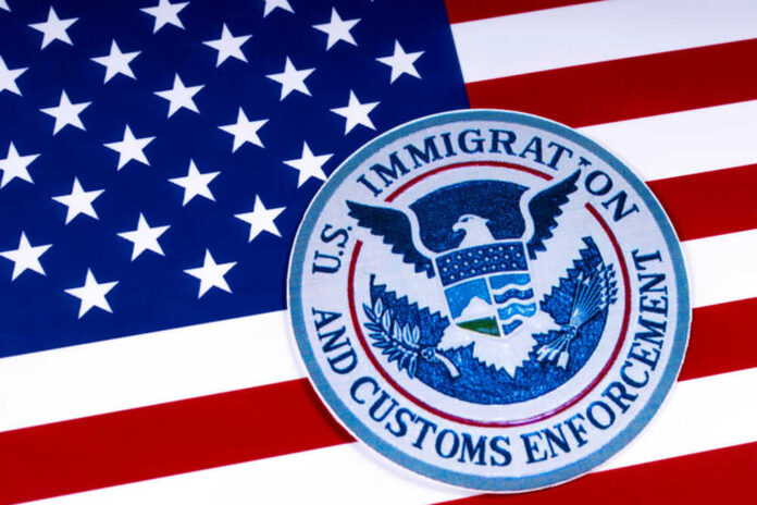 shutterstock_1055129177.jpg US Immigration and Customs Enforcement badge on flag