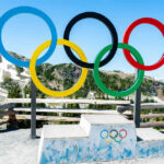 Olympic Icon’s Courageous Message Defies Critics Olympic rings and podium with mountain backdrop.