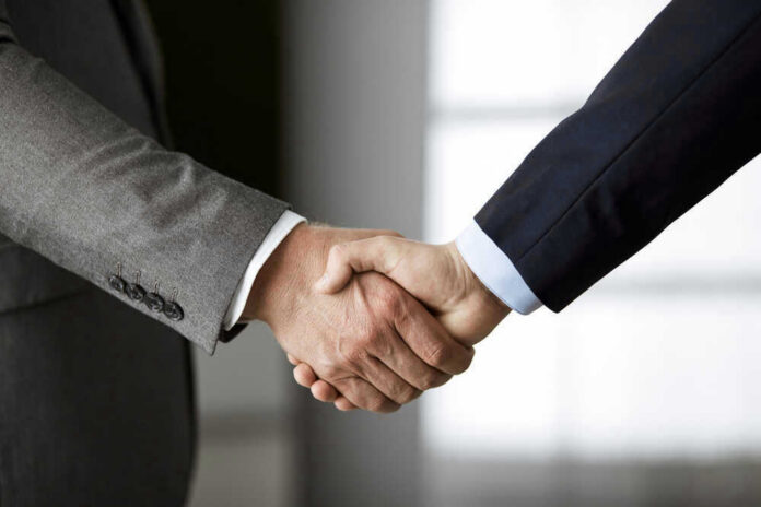 Two people in business suits shaking hands.