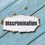 White Discrimination Charges Hit Huge American Employer A torn paper with the word 'Discrimination' on a blue wooden background