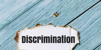 A torn paper with the word 'Discrimination' on a blue wooden background