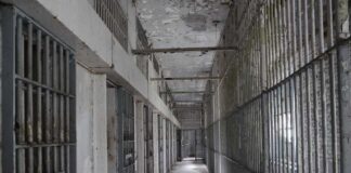 Empty prison corridor with barred cells on either side