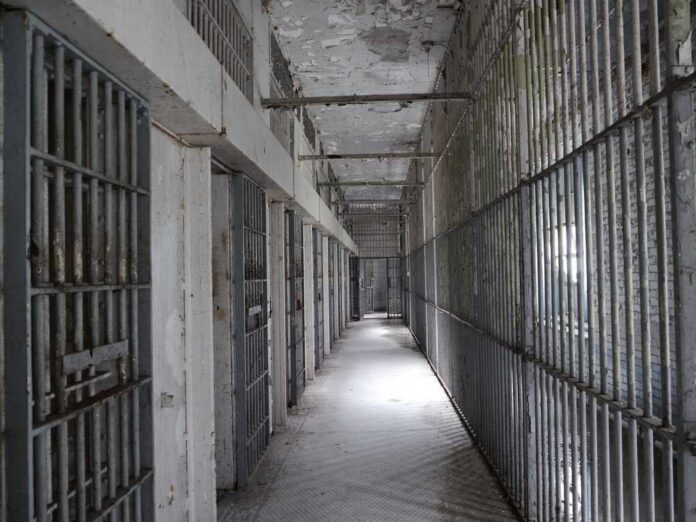 Empty prison corridor with barred cells on either side