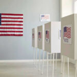 Polling booths with American flags and Vote signs.