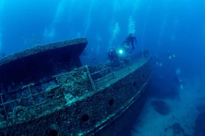 Divers exploring a sunken shipwreck underwater