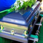 Legendary Rock Vocalist Dies at 83 A silver casket adorned with flowers at a gravesite
