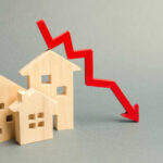 Wooden model houses with a red downward trend arrow