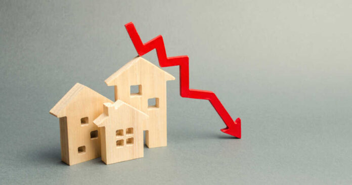 Wooden model houses with a red downward trend arrow