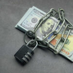 A stack of cash secured with a chain and padlock