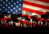 Silhouettes of protesters holding signs in front of an American flag