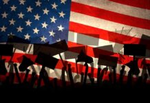 Silhouettes of protesters holding signs in front of an American flag