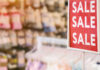 Red sale sign in a clothing store with various items in the background