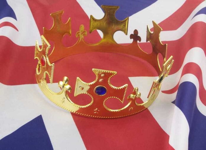 shutterstock_2065165385.jpg Gold crown on a Union Jack flag.