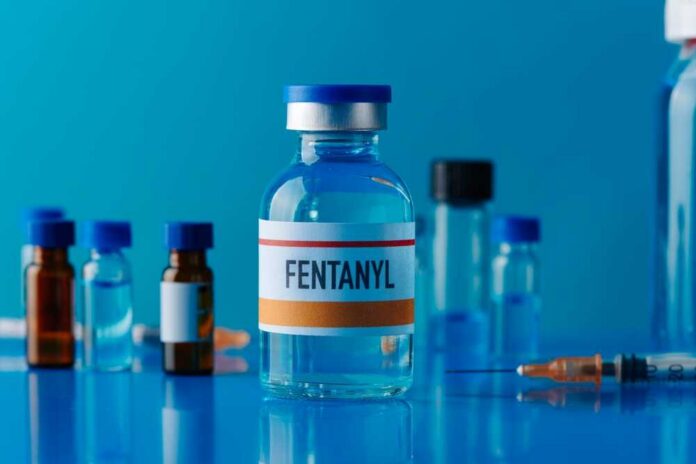 A vial labeled Fentanyl surrounded by various medical containers and a syringe