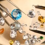 A blue gemstone being held with tweezers among various other gemstones