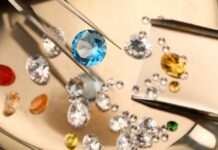 A blue gemstone being held with tweezers among various other gemstones