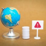 Choke Point Sparks Oil Panic A miniature globe next to a warning sign and a barrel
