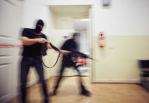 Two masked individuals with guns moving quickly in a hallway