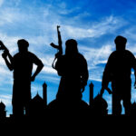 ISIS Felon Gets Gun Anyway, Commits Murder Silhouetted figures holding weapons against a blue sky