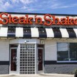 Exterior view of a Steak 'n Shake restaurant with a striped awning