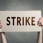 Two hands holding cardboard sign with strike text