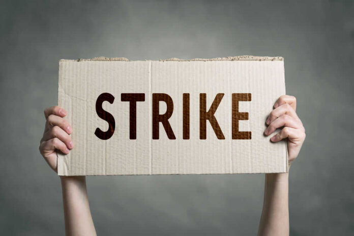 shutterstock_683350906.jpg Two hands holding cardboard sign with strike text