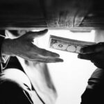 BIDEN Gutted Fraud Controls — BILLIONS Stolen Hands passing money under a table, shrouded in mystery.