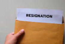 A hand holding an envelope with a resignation letter partially visible