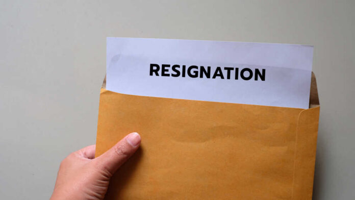 A hand holding an envelope with a resignation letter partially visible