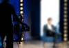 Person being filmed on a set with lights.