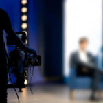 Regulatory Earthquake Hits Broadcasting Titan Person being filmed on a set with lights.