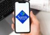 A hand holding a smartphone displaying the Sam's Club logo