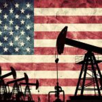 Silhouettes of oil pumps in front of a distressed American flag