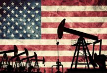 Silhouettes of oil pumps in front of a distressed American flag