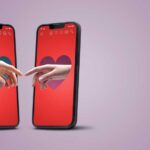 Two smartphones displaying hands reaching towards each other with heart backgrounds