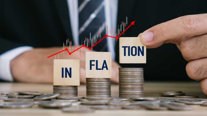 Blocks spelling 'INFLATION' placed on stacks of coins with a rising graph in the background