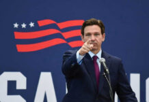 Governor of Florida, Ron DeSantis points forward at podium.